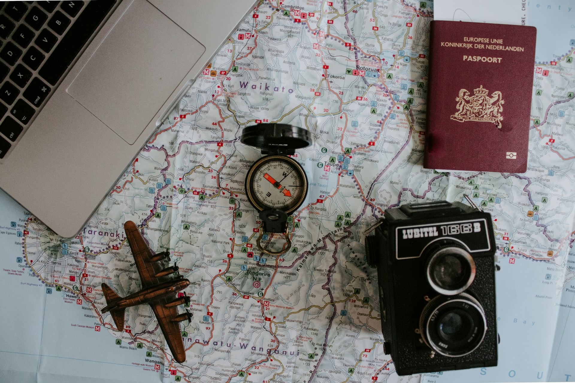 Planing to travel to new zealand with passport a map and laptop on a table