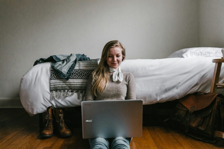 a remote worker sitting by her bed and getting work done